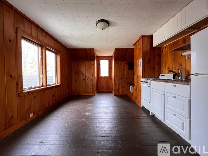 A kitchen with wooden walls and a white fridge.