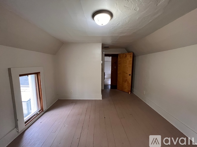 A room with wooden flooring and a window on the left side.