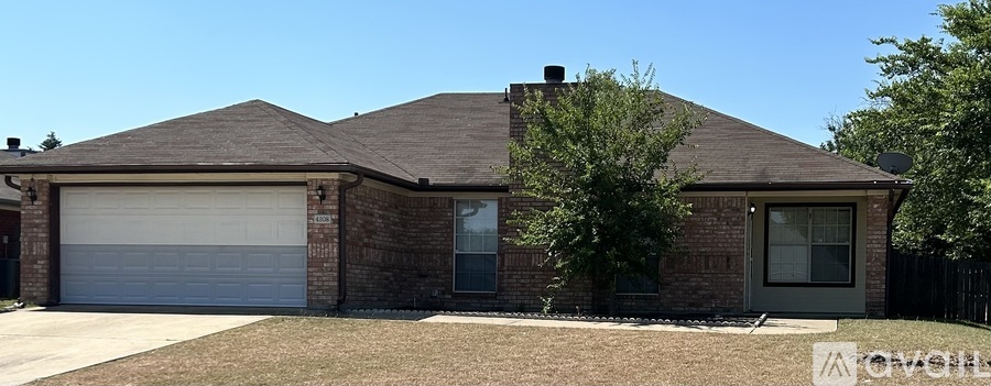 A house with a garage door and a tree in front.