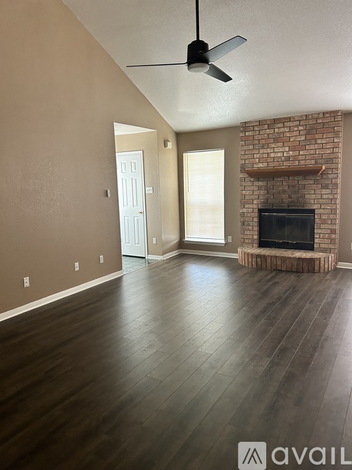 A living room with a fireplace and a ceiling fan.