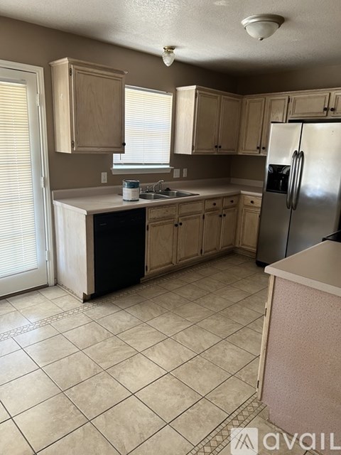 A kitchen with a refrigerator, sink, and cabinets.