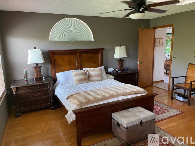 A bedroom with a large bed and a ceiling fan.