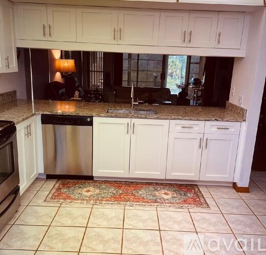 A kitchen with white cabinets and a rug on the floor.