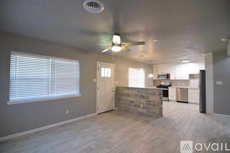 A spacious living room with a ceiling fan and a stone fireplace.