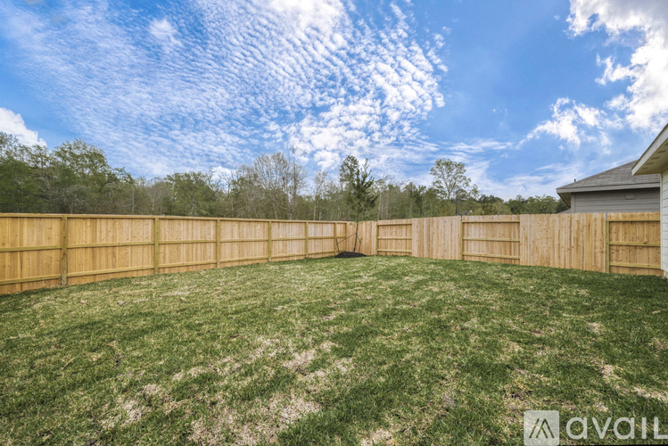 A backyard with a wooden fence and a house in the background.