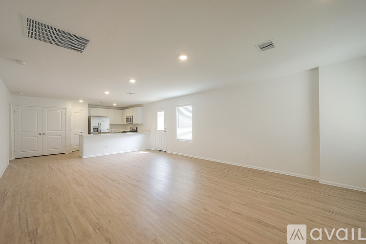 A spacious room with wooden flooring and white walls.
