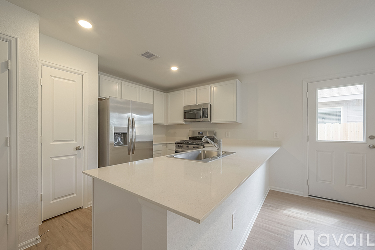 A kitchen with white cabinets and a stainless steel refrigerator.