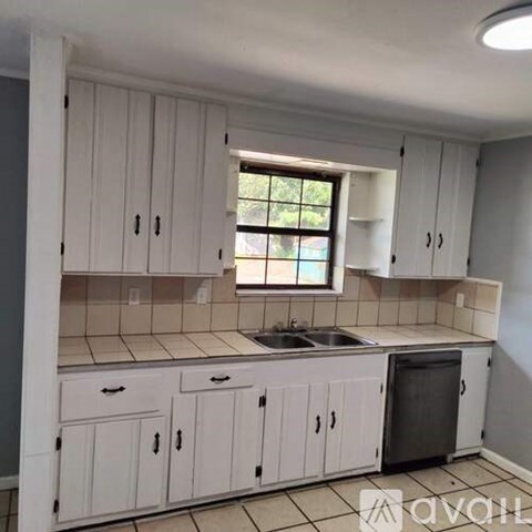 A kitchen with white cabinets and a window.
