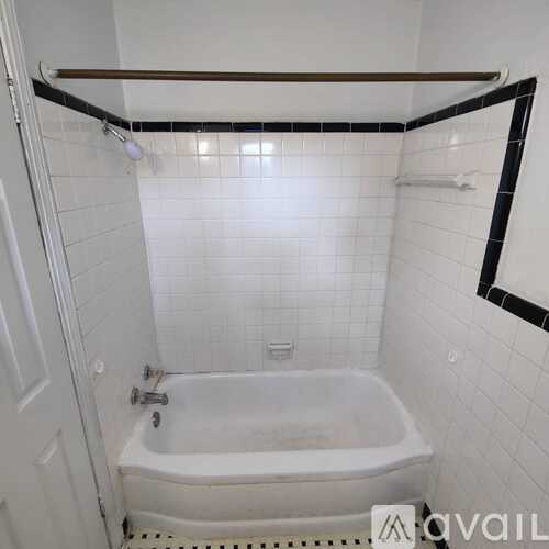 A white bathroom with a white tub and white tiles.