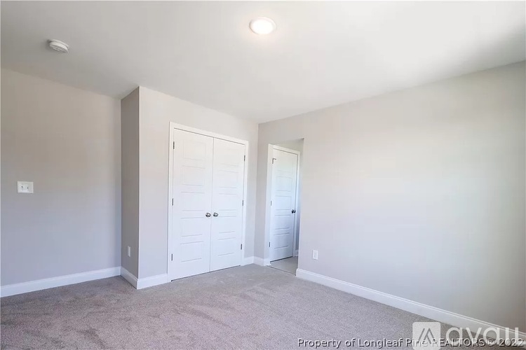 A bedroom with a carpeted floor and two doors.