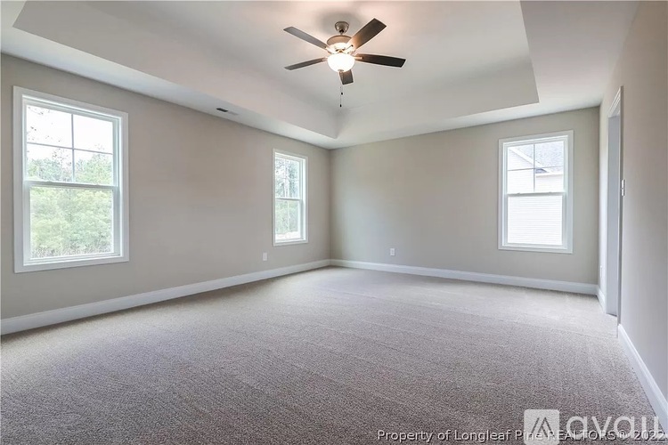 A spacious room with a ceiling fan and carpeted floor.