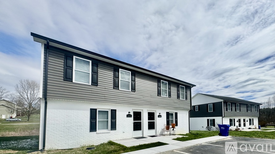 A row of houses with the first one on the left being a two story white house with a black door and windows.