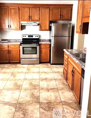 A kitchen with wooden cabinets and a tile floor.