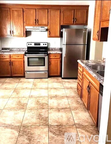 A kitchen with wooden cabinets and a tile floor.