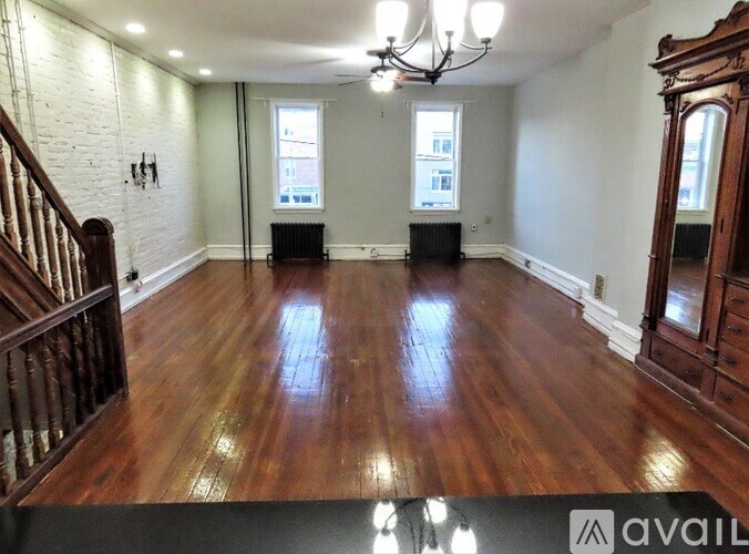 A room with wooden floors and a staircase on the left side.