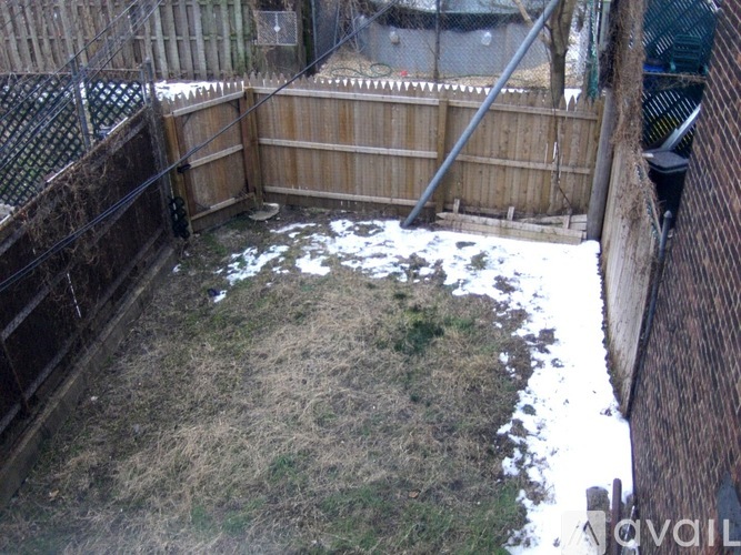 A backyard with a wooden fence and a small patch of grass.