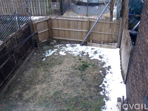 A backyard with a wooden fence and a small patch of grass.