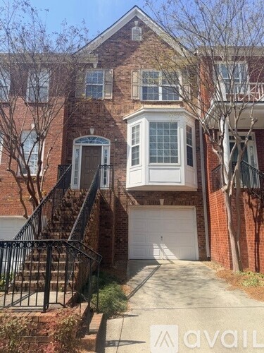 A brick house with a white garage door and a black metal railing.