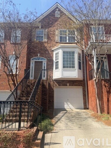 A brick house with a white garage door and a black metal railing.