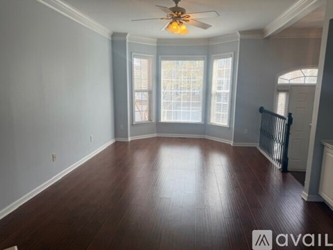 A spacious room with a ceiling fan and wooden flooring.