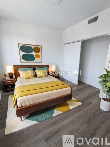 A bedroom with a bed, nightstand, and a plant.
