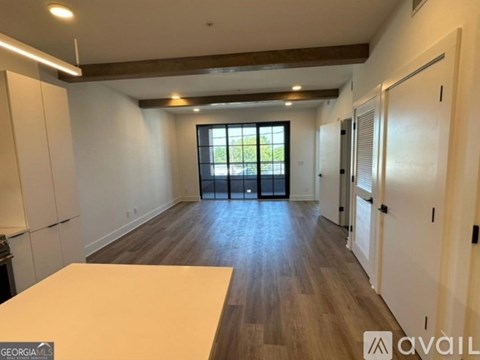 A spacious room with wooden floors and a large window.