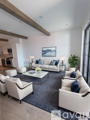 A modern living room with white furniture and a large painting on the wall.