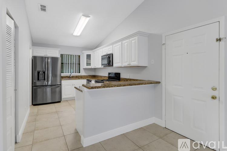 A kitchen with white cabinets and a granite countertop.