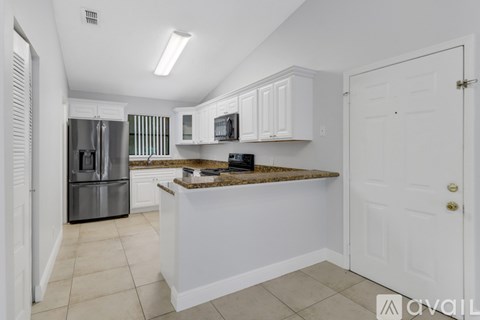 A kitchen with white cabinets and a granite countertop.