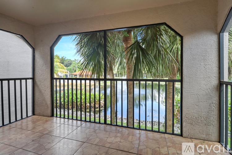 A balcony with a view of a pool and palm trees.