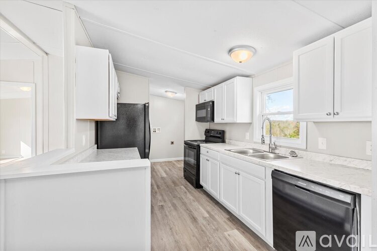 A kitchen with white cabinets and a black refrigerator.