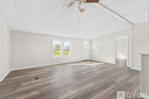 A spacious room with wooden flooring and a ceiling fan.