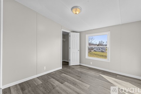 A room with a door and a window showing a car and trees outside.