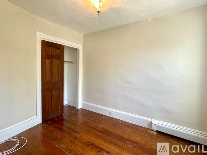 A room with a wooden door and a white wall.
