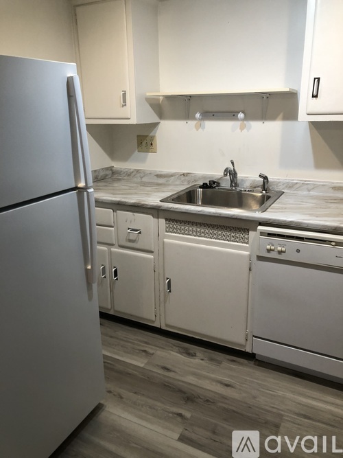 A kitchen with a refrigerator, sink, and cabinets.