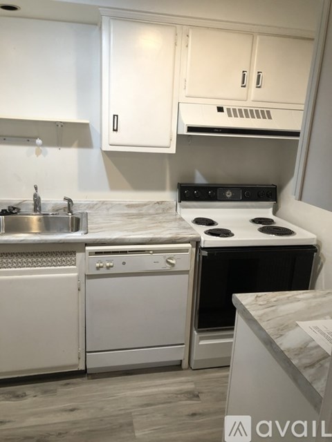 A kitchen with white cabinets and a marble countertop.