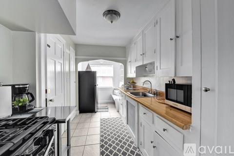 A kitchen with a black stove top oven and white cabinets.
