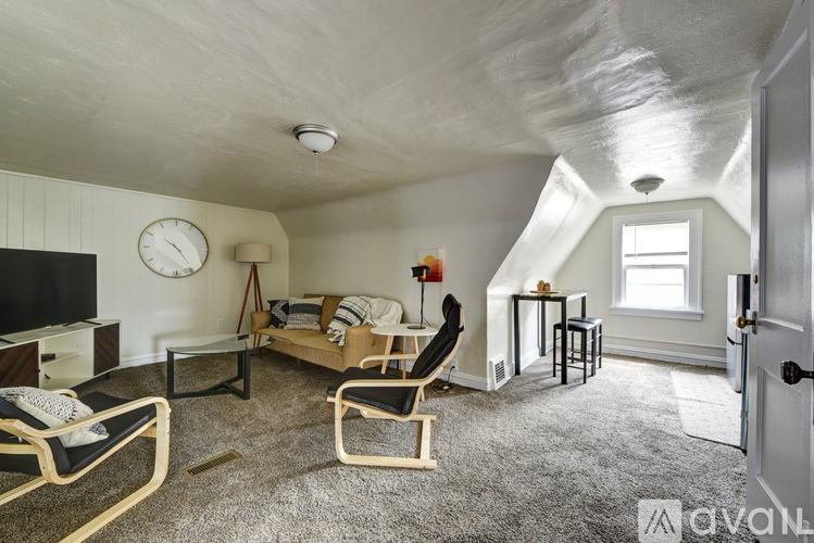 A living room with a couch, chairs, and a television.