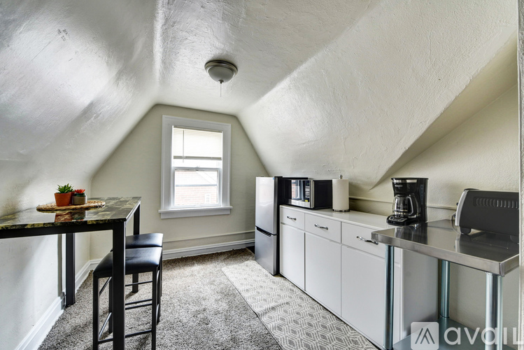 A kitchen area with a table and chairs, a window, and a counter with a coffee maker.