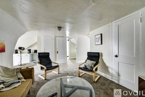 A living room with a glass table and two chairs.