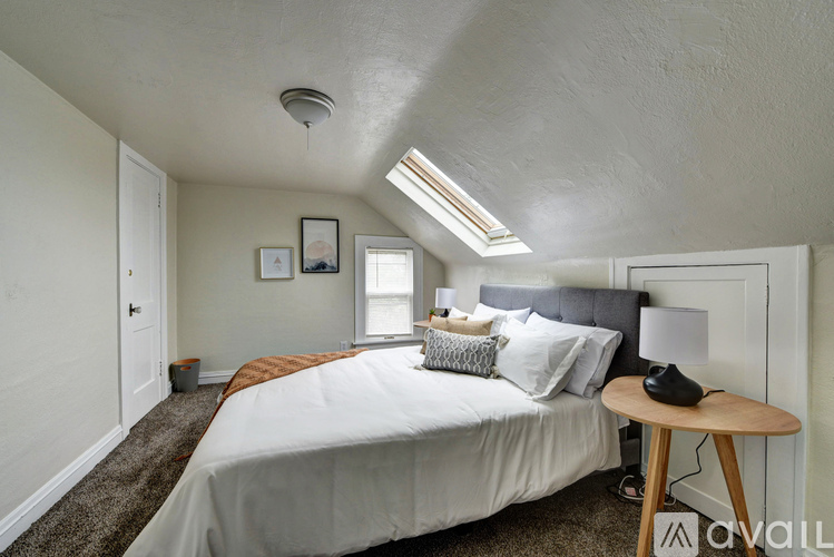 A bedroom with a bed, a nightstand, and a window.