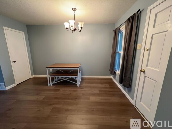 A room with a wooden floor and a table with a white frame.