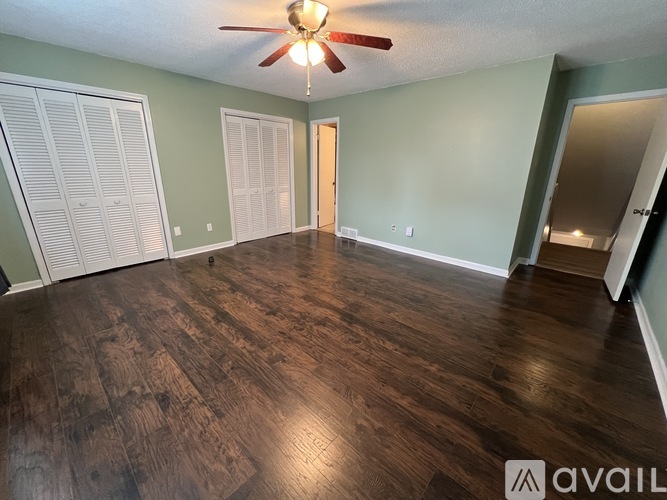 A room with a ceiling fan and wood flooring.