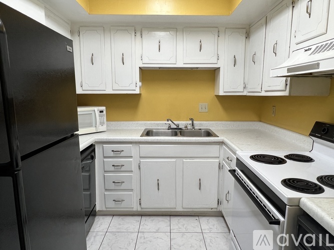 A kitchen with white cabinets and a black refrigerator.