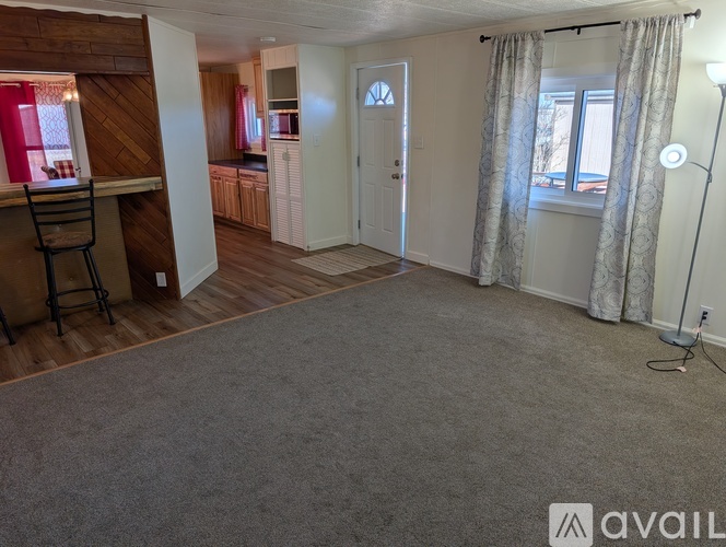 A living room with a grey carpet and a white door.