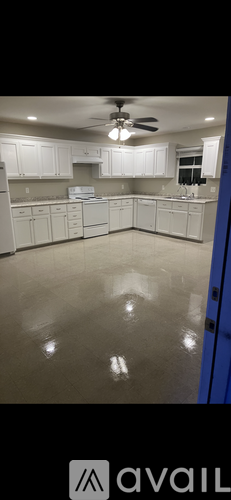 A spacious kitchen with white cabinets and a ceiling fan.