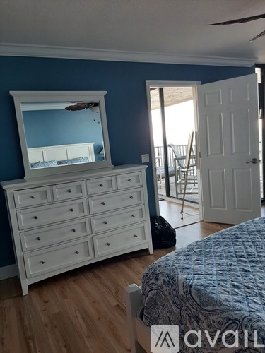 A bedroom with a white dresser and a mirror.
