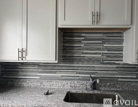 A kitchen with white cabinets and a black countertop.