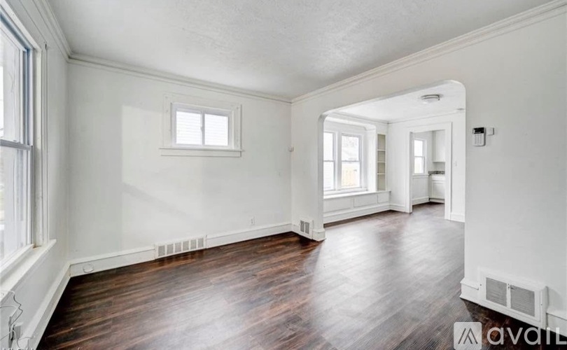 A spacious room with wooden floors and white walls.