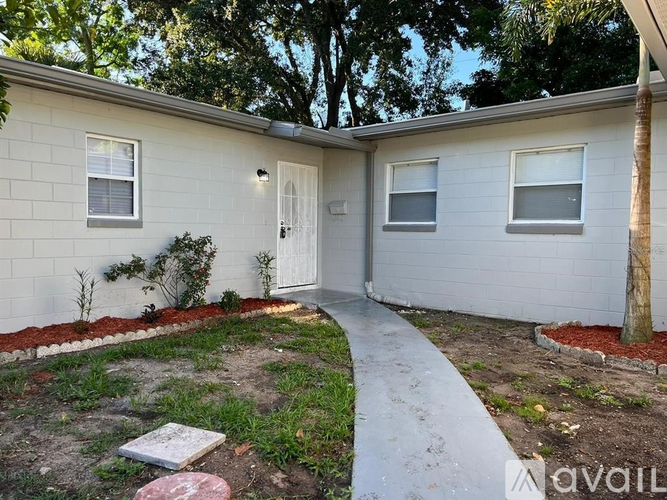 A small white house with a red brick border around the front yard.